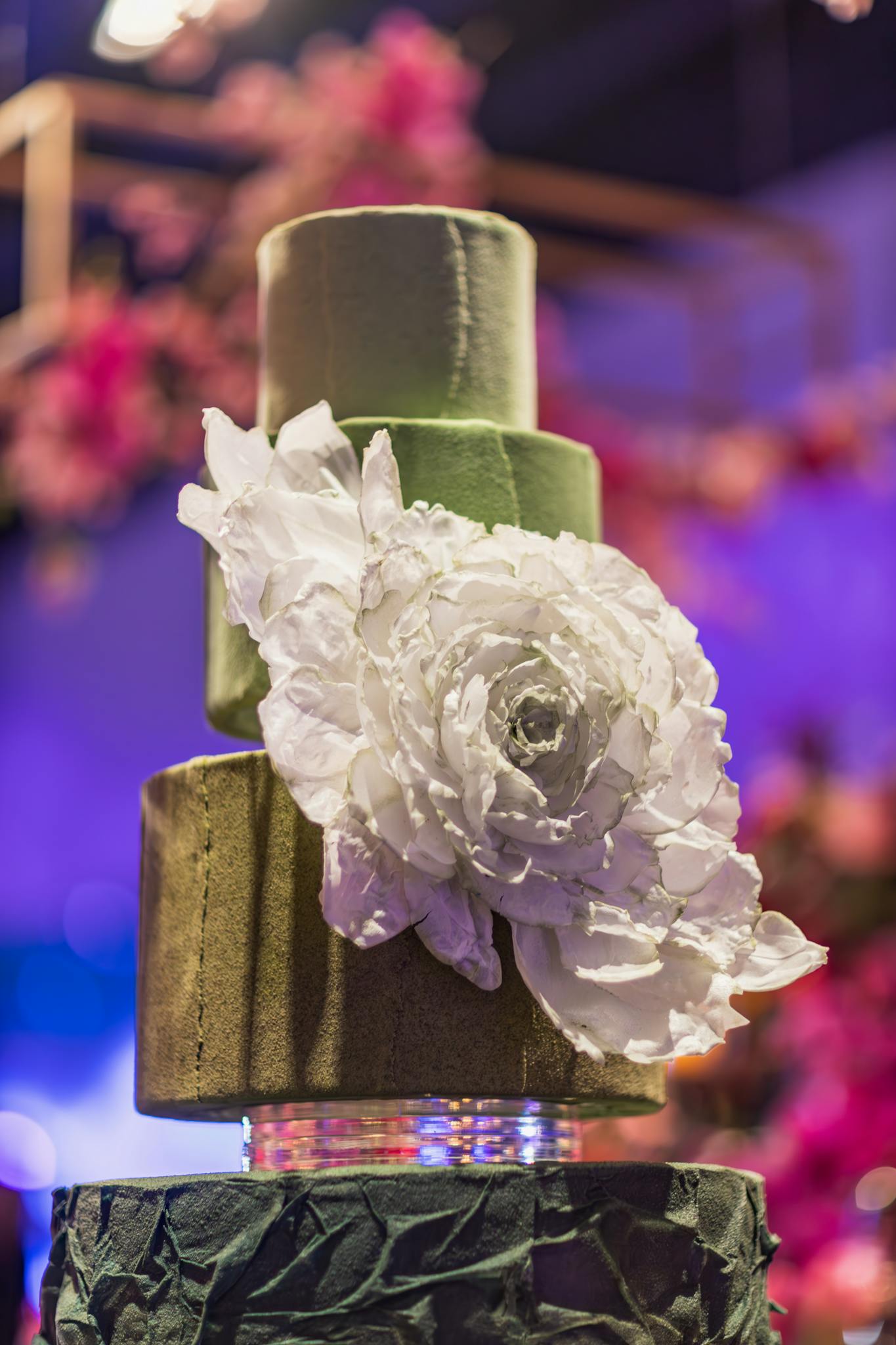 A stunning green three-tier cake adorned with elegant white flower decoration, perfect for celebrations.