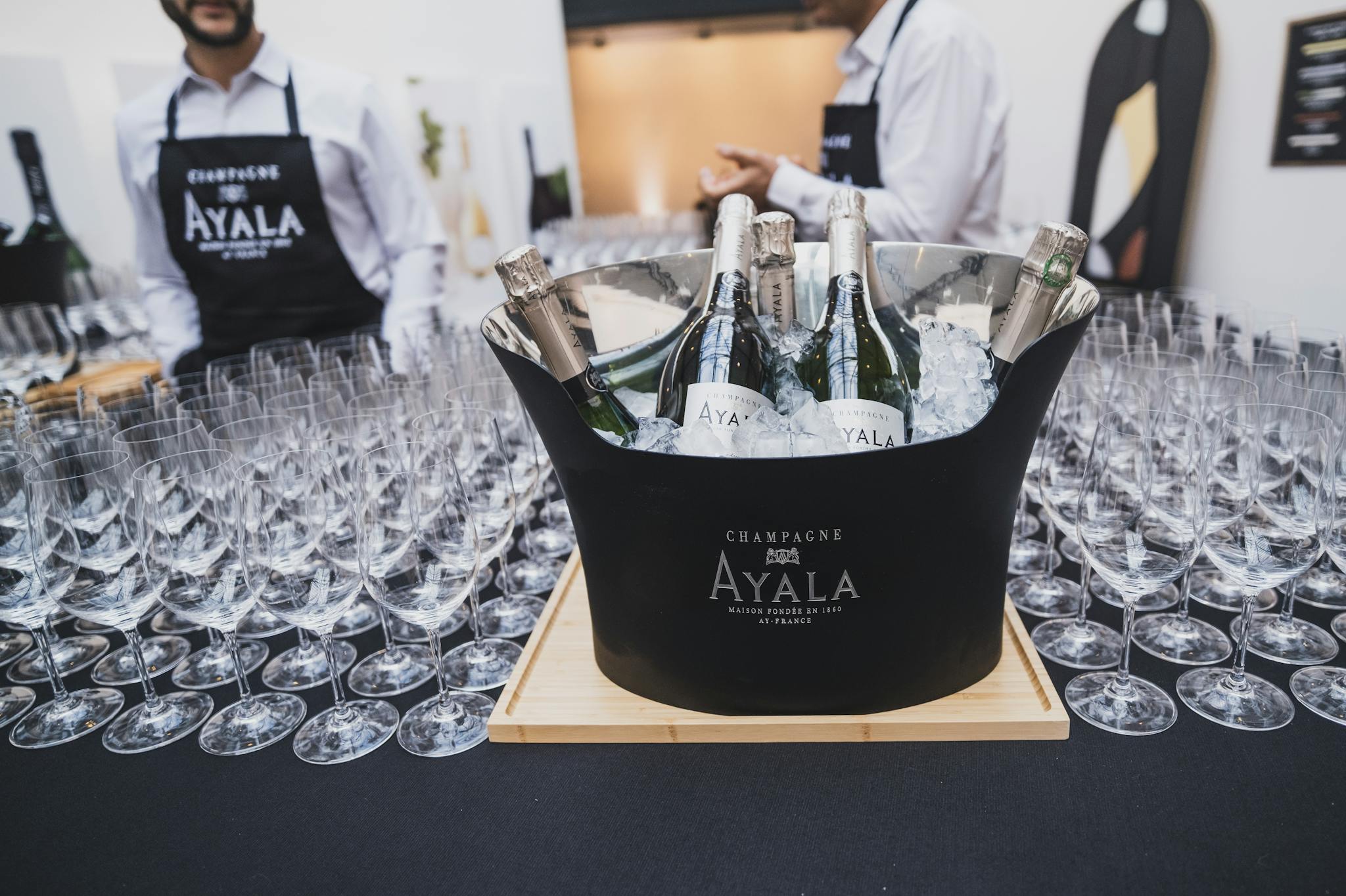 Chilled champagne bottles in ice bucket surrounded by empty wine glasses at elegant indoor event.